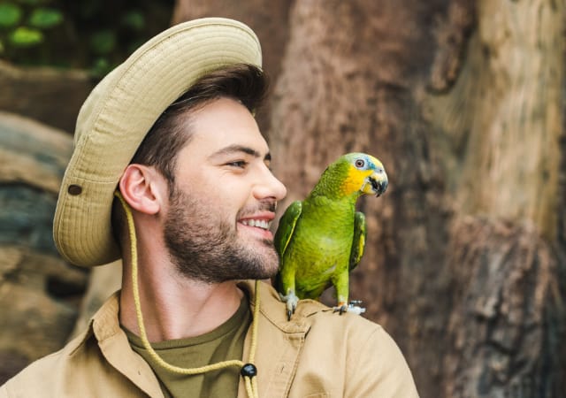 A person with a parrot perched on his shoulders in the outdoors